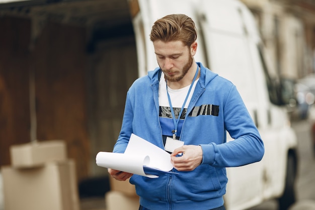 Mann am LKW. Mann in einer Lieferuniform. Mann mit Zwischenablage.