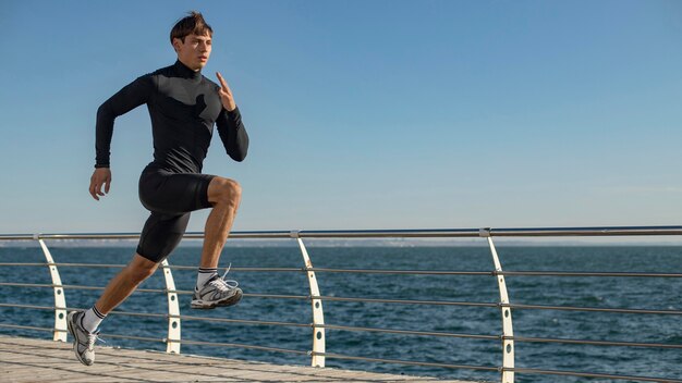 Mann am Strand, der in Aktivkleidung joggt