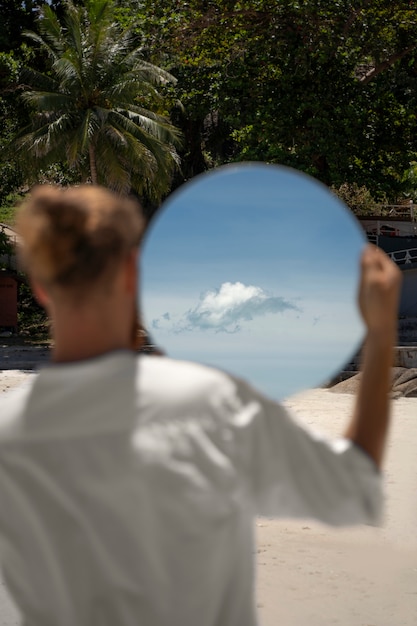 Mann am Strand posiert mit rundem reflektierendem Spiegel