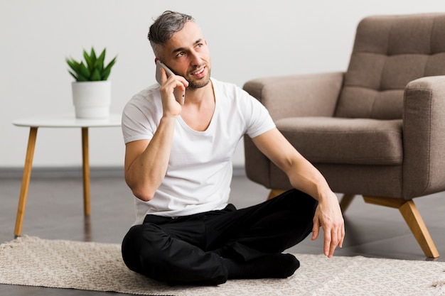 Mann am Telefon sprechen und sitzen auf dem Boden