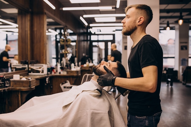 Kostenloses Foto mann an einem friseursalon, der haarschnitt und bartschnitt tut