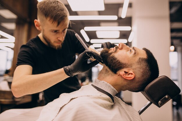 Mann an einem Friseursalon, der Haarschnitt und Bartschnitt tut