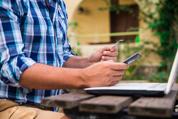 Mann arbeitet am laptop aus garten. zählen von finanzdaten bank, banken, rechnung.