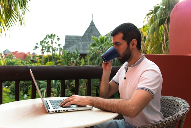 Mann arbeitet mit seinem laptop auf einer hotelterrasse