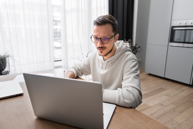 Mann arbeitet von zu Hause aus am Schreibtisch mit Laptop