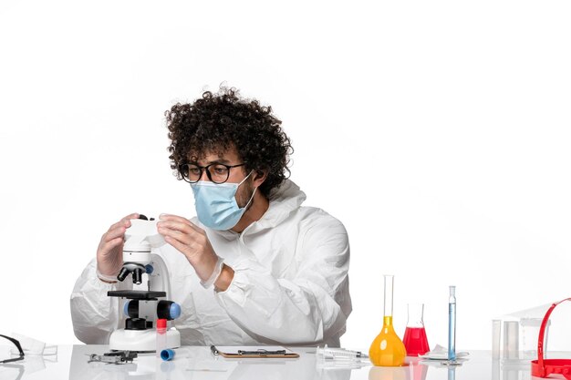 Mann Arzt in Schutzanzug und Maske arbeitet mit Mikroskop auf Weiß