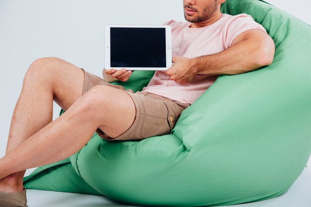 Mann auf Couch mit Tablette Schaufenster Konzept