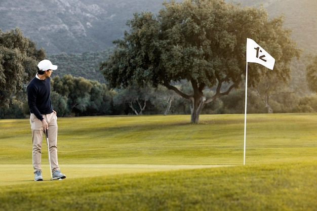 Mann auf dem Golfplatz neben Flagge