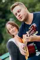 Kostenloses Foto mann auf der bank, die gitarre spielt und singt