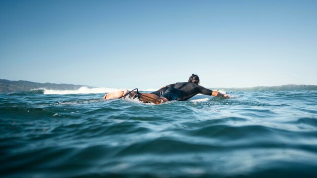 Mann auf seinem Surfbrett schwimmt Long Shot