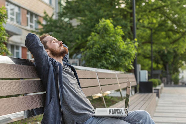 Mann auf Stadtbank mit Laptop