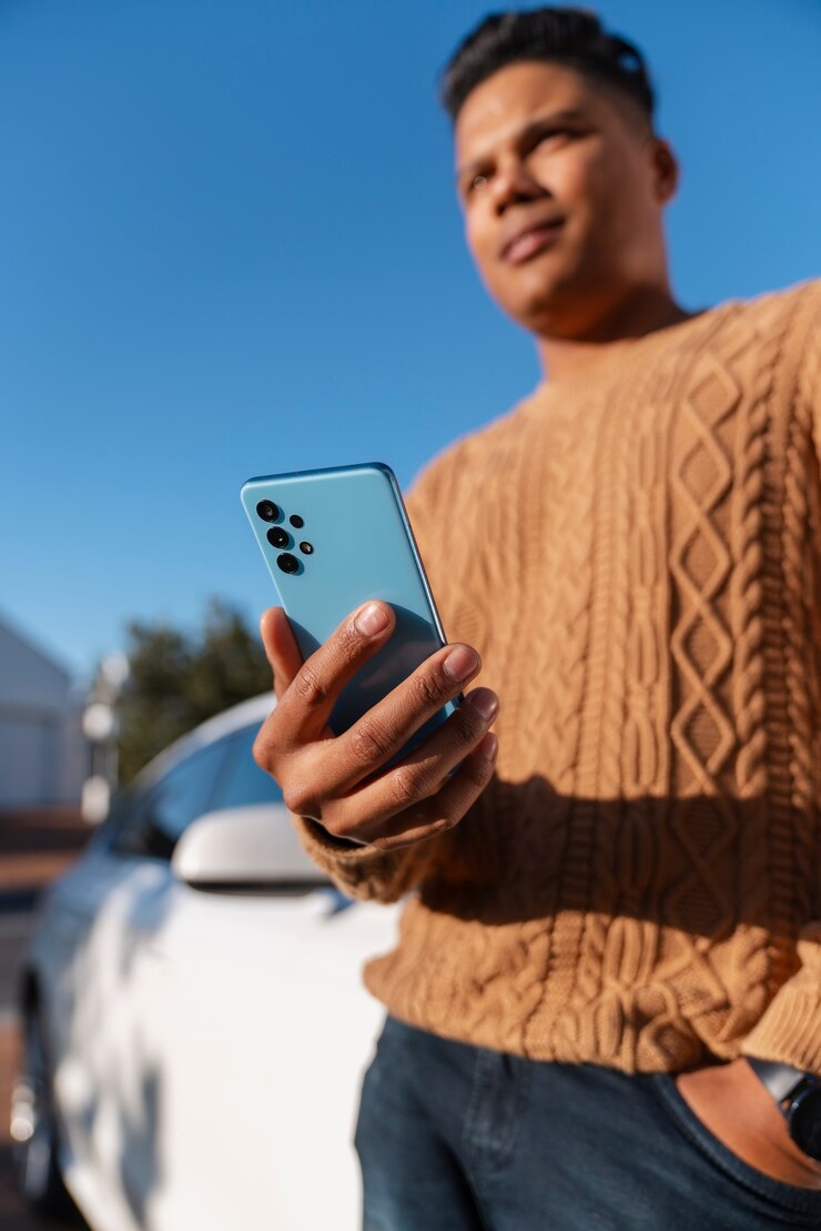 Kostenlose Foto mann aus niedrigem winkel benutzt smartphone im freien