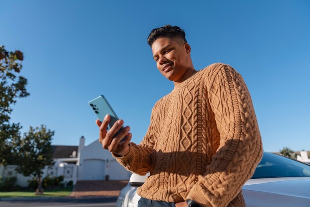 Kostenloses Foto mann aus niedrigem winkel benutzt smartphone im freien