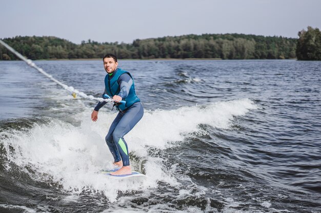 Mann beim Wakesurfen. winken vom Boot.