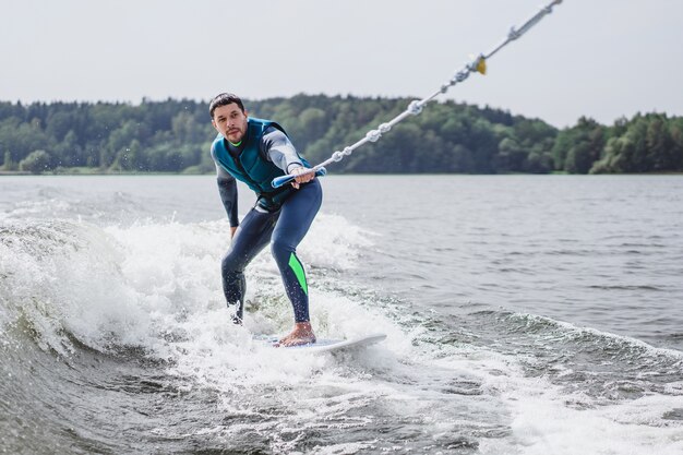 Mann beim Wakesurfen. winken vom Boot.