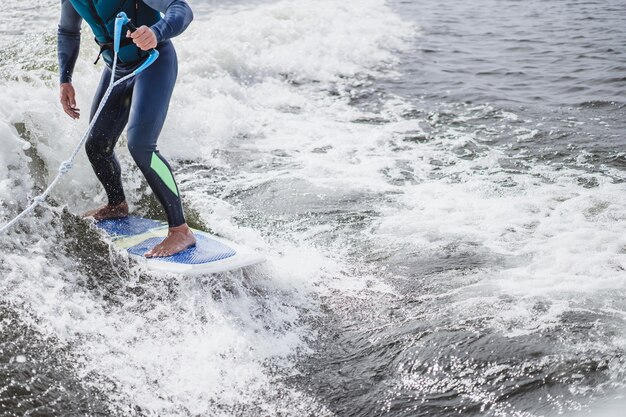 Mann beim Wakesurfen. winken vom Boot.