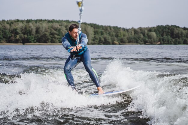 Mann beim Wakesurfen. winken vom Boot.