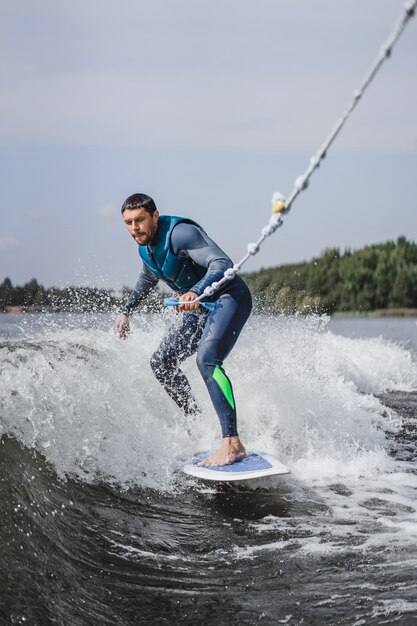 Mann beim Wakesurfen. winken vom Boot.