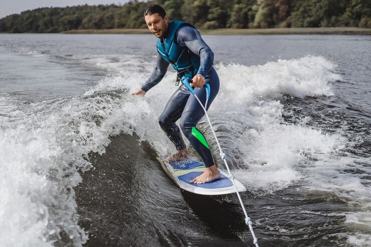 Kostenlose Foto mann beim wakesurfen. winken vom boot.