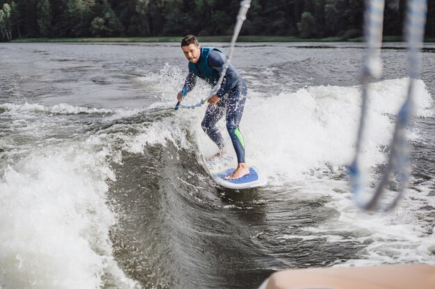 Mann beim Wakesurfen. winken vom Boot.