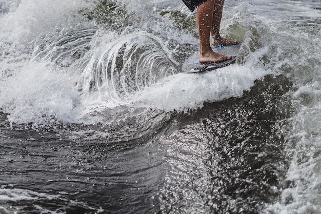 Mann beim Wakesurfen. winken vom Boot.