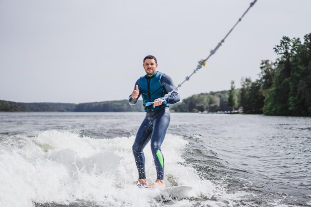 Mann beim Wakesurfen. winken vom Boot.