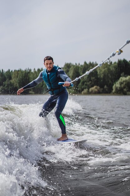 Mann beim Wakesurfen. winken vom Boot.