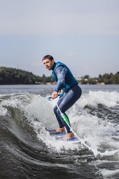 Mann beim Wakesurfen. winken vom Boot.