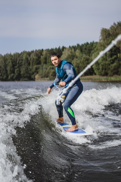 Mann beim Wakesurfen. winken vom Boot.