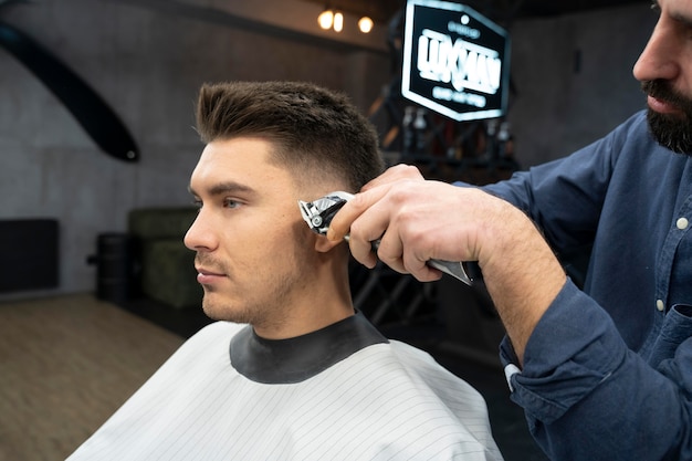 Kostenloses Foto mann bekommt einen haarschnitt im salon mittlerer schuss