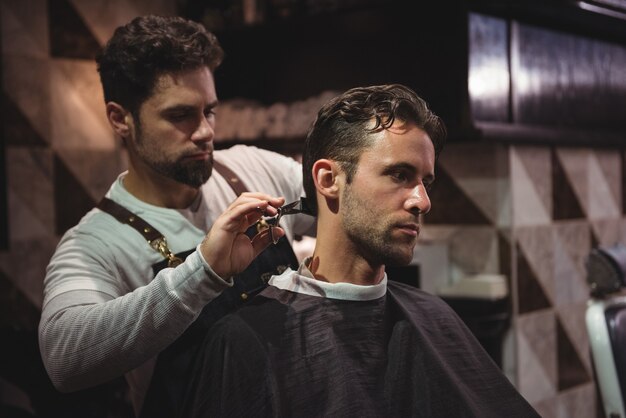 Mann bekommt seine Haare mit einer Schere geschnitten