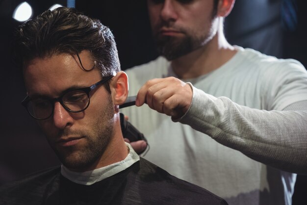 Mann bekommt seine Haare mit Trimmer geschnitten