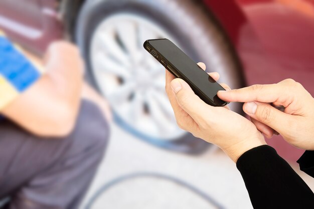 Mann benutzt Handy anrufen jemand über Reifenpannehintergrund des Autos