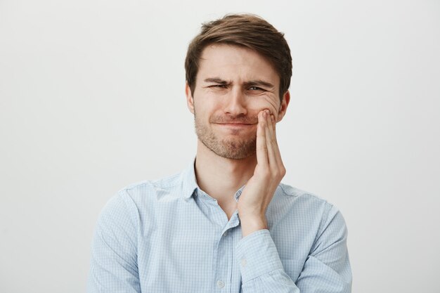Mann berührt Wange und verzog das Gesicht vor Schmerzen durch Zahnschmerzen