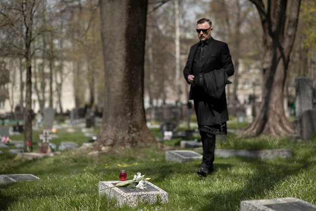 Mann besucht Grabstein auf dem Friedhof