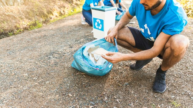 Mann, der Abfall in der Plastiktasche sammelt