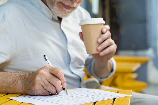 Mann, der alleine ein Sudoku-Spiel auf Papier genießt