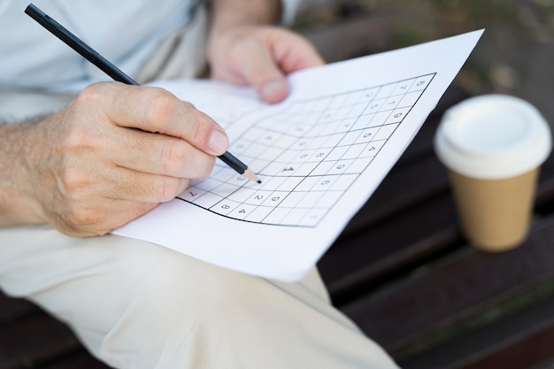 Mann, der alleine ein Sudoku-Spiel auf Papier genießt