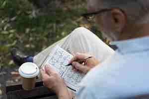 Kostenloses Foto mann, der alleine ein sudoku-spiel auf papier genießt