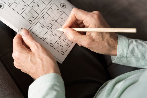 Mann, der alleine ein Sudoku-Spiel auf Papier genießt