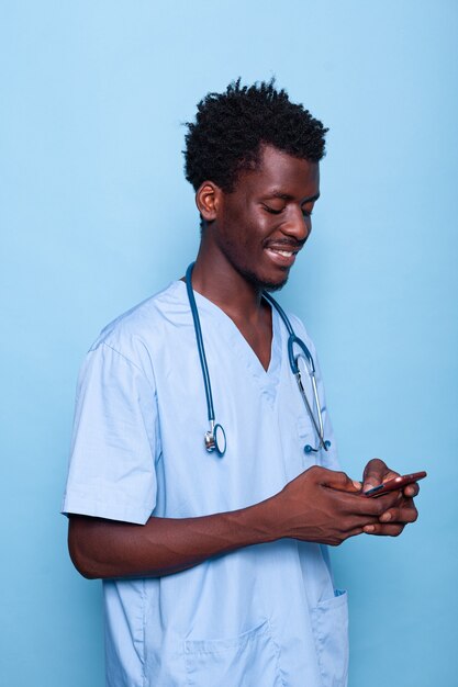 Mann, der als Krankenschwester arbeitet und auf Smartphone schaut und lächelt