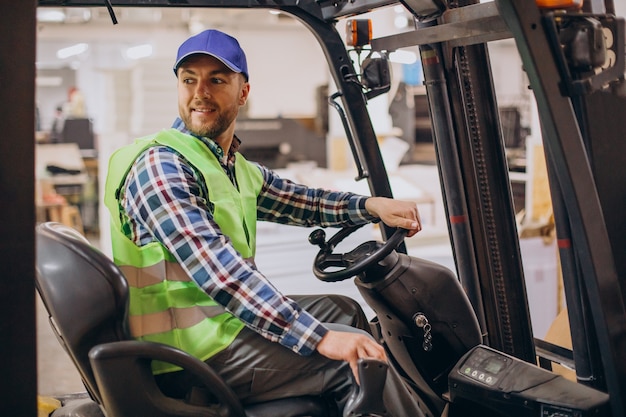 Mann, der am Lager arbeitet und Gabelstapler fährt