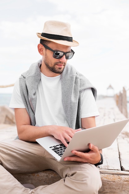 Mann, der am Laptop am Strand arbeitet