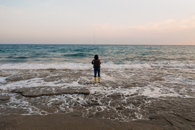 Mann, der am Seeufer fischt