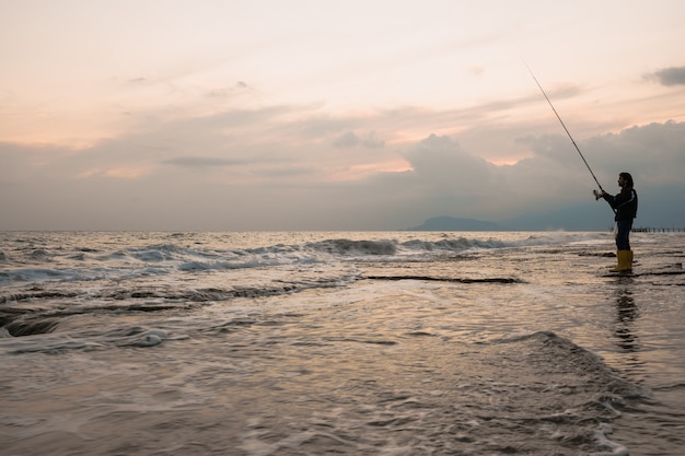 Mann, der am Seeufer fischt