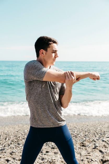 Mann, der am Strand ausdehnt