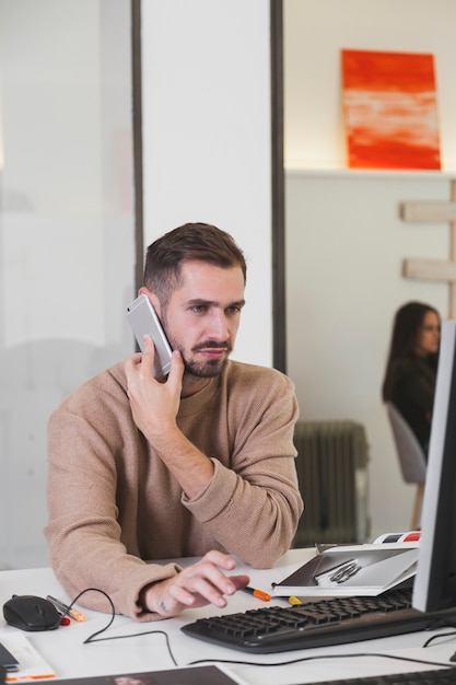 Mann, der am Telefon am Computer spricht