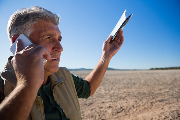 Mann, der am Telefon bei der Stellung auf Landschaft spricht