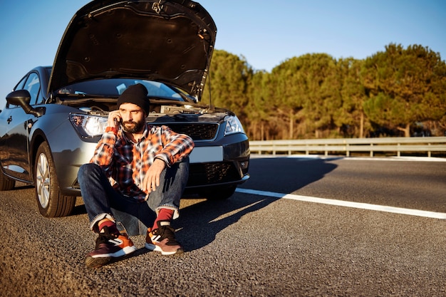 Mann, der am Telefon neben Auto spricht