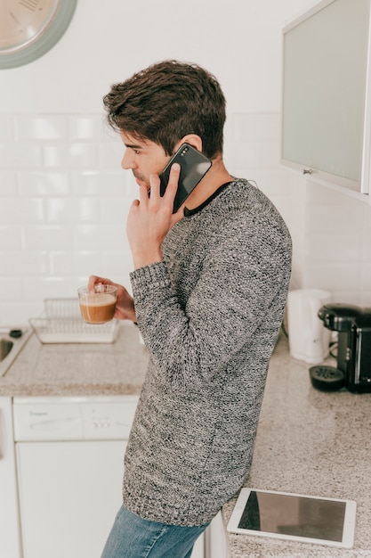 Mann, der am Telefon spricht und Kaffee trinkt